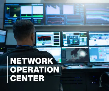 A network operations center (NOC) specialist is seen from behind, monitoring multiple high-resolution screens displaying real-time data, system performance graphs, security metrics, and maritime surveillance maps. The dimly lit control room is filled with an array of monitors, creating a high-tech and secure environment. Large, bold white text on the left side of the image reads "NETWORK OPERATION CENTER", emphasizing the critical role of real-time monitoring and cybersecurity in offshore and maritime operations.