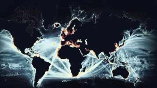 A digital visualization of global maritime traffic, showing a world map with illuminated shipping routes crisscrossing the oceans. The brightest areas, particularly along coastlines and major trade hubs, indicate high-density maritime activity. The glowing white and orange lines contrast sharply against the dark background, emphasizing the vast and interconnected nature of global shipping networks. The image highlights the strategic importance of maritime surveillance and monitoring in ensuring secure and efficient global trade.