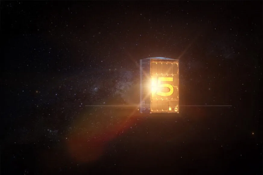 A glowing satellite with the number "5" illuminated in golden light floats in the vastness of space, surrounded by a star-filled cosmic background. The satellite appears to be a small, cube-shaped spacecraft, possibly a CubeSat, with solar panels on its sides. A bright light source reflects off its surface, enhancing the futuristic and high-tech aesthetic. The image symbolizes the launch or milestone achievement of BRO-5, part of the Unseenlabs satellite constellation.