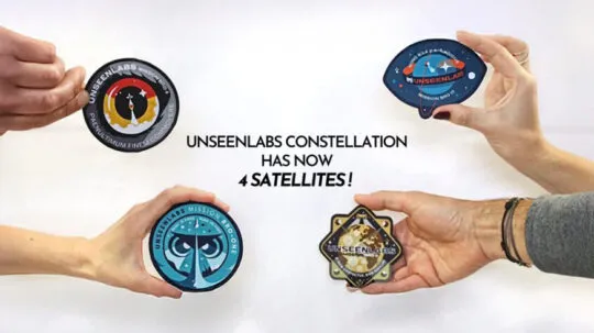 Four hands hold different mission patches representing Unseenlabs' satellites against a white background. Each patch has a distinct design, symbolizing a different mission. In the center, bold black text announces: "UNSEENLABS CONSTELLATION HAS NOW 4 SATELLITES!" The image visually highlights the growth of Unseenlabs' satellite constellation.