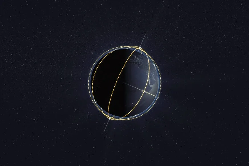 A digital illustration of Earth in space, partially illuminated by the sun. Several dotted yellow lines wrap around the planet, representing satellite orbits in different planes. The background is filled with stars, emphasizing the space environment.
