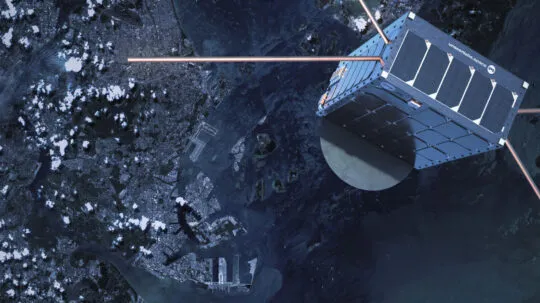A high-resolution image of an Unseenlabs satellite orbiting Earth, showcasing its cubic design, solar panels, and extended antennas for radio frequency (RF) detection. The satellite is positioned above a coastal city with harbors and waterways visible below, emphasizing its role in maritime surveillance. The satellite's shadow is cast on its metallic surface, while the Earth’s surface, scattered with clouds, provides a striking contrast. This image highlights Unseenlabs’ space-based intelligence capabilities in tracking and monitoring vessels across global waters.