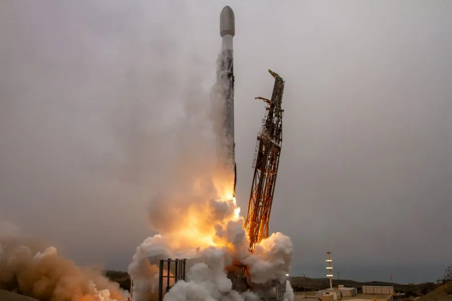 Falcon with BRO-18 inside Launch captured at liftoff, with flames and smoke billowing from the base against a cloudy sky.
