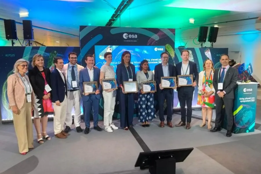 Group photo of award recipients and ESA representatives at the Living Planet Symposium 2025, holding certificates in front of a Copernicus-themed backdrop.