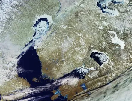 A high-resolution satellite image of northeastern Europe, showcasing a winter landscape with ice-covered lakes, snow-covered land, and partially frozen coastlines. The image highlights natural geographic features, including bodies of water and land formations, with a mix of white, blue, and earthy tones. Contains modified Copernicus Sentinel data (2021), processed by ESA