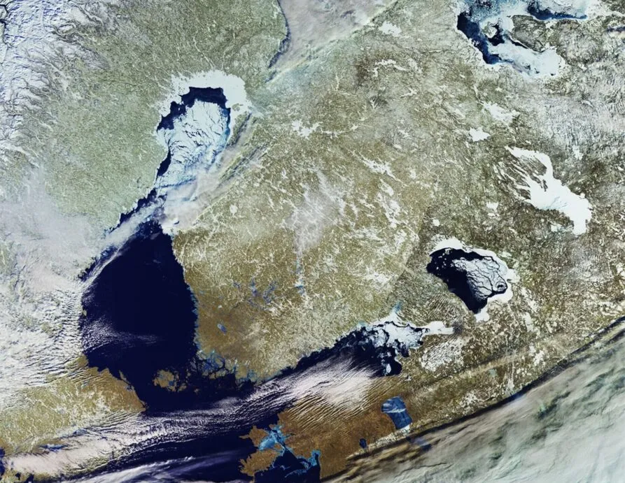 A high-resolution satellite image of northeastern Europe, showcasing a winter landscape with ice-covered lakes, snow-covered land, and partially frozen coastlines. The image highlights natural geographic features, including bodies of water and land formations, with a mix of white, blue, and earthy tones. Contains modified Copernicus Sentinel data (2021), processed by ESA