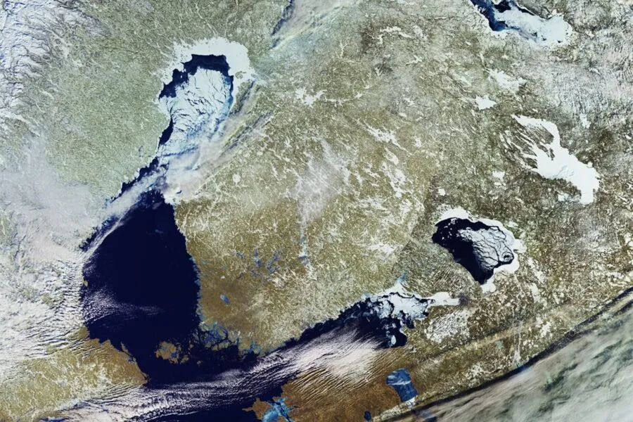 A high-resolution satellite image of northeastern Europe, showcasing a winter landscape with ice-covered lakes, snow-covered land, and partially frozen coastlines. The image highlights natural geographic features, including bodies of water and land formations, with a mix of white, blue, and earthy tones. Contains modified Copernicus Sentinel data (2021), processed by ESA